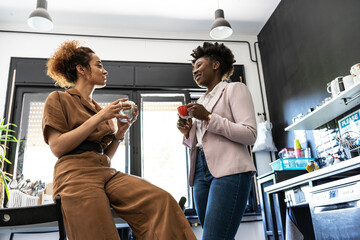 Two female employees on coffee break in company lunchroom.