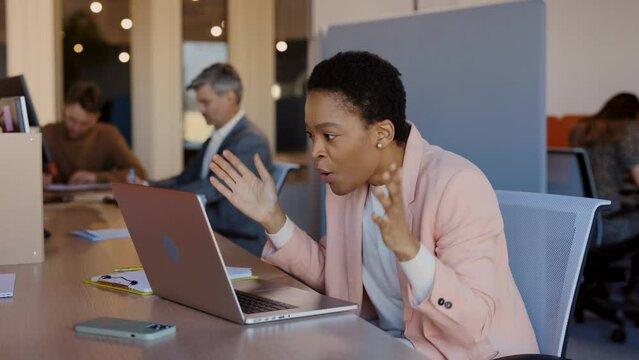 Excited young woman looking at laptop screen, celebrating win, showing yes gesture, while sitting at desk in office. Businesswoman rejoicing success and reading good news email.