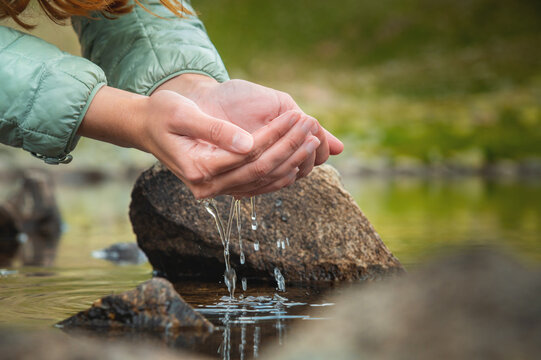 Close-up of a woman's hand pouring water from her palms while trying to drink from a clean water source in nature