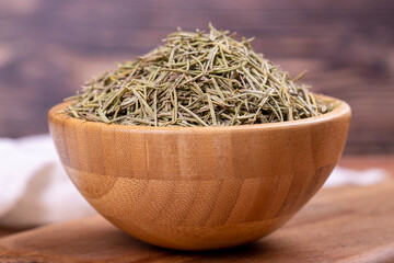 Dried herbs rosemary leaf. Dry seasoning rosemary on wood background. Spices and herbs for cooking, provence herbs. Close up