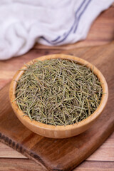 Dried herbs rosemary leaf. Dry seasoning rosemary on wood background. Spices and herbs for cooking, provence herbs. Close up