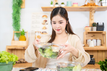 Young asian woman eating healthy food with salad vegetables. woman sitting at pantry in a beautiful...