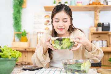 Smiling woman eating fresh healthy salad vegetables. woman sitting at pantry in a beautiful...