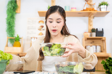 Smiling woman eating fresh healthy salad vegetables. woman sitting at pantry in a beautiful...