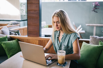 Young hipster girl with digital netbook chatting and messaging in social media networks, Caucasian female blogger making online booking via wireless application on modern netbook device technology