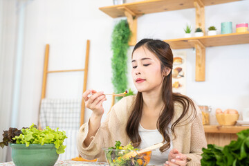 Smiling woman eating fresh healthy salad vegetables. woman sitting at pantry in a beautiful...