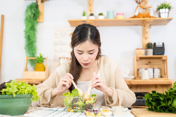 Young asian woman eating healthy food with salad vegetables. woman sitting at pantry in a beautiful...