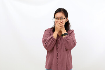 Young asian woman covering her mouth while glancing beside her. Isolated on white background