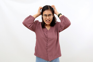 Stressed young asian woman shouting while holding her head. Isolated on white background