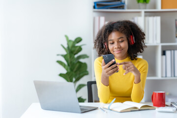 Fototapeta premium Cute young woman curly hair wearing headphones using smartphone to listen to music happy and relax listening to music at home.