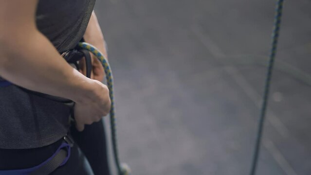 Tightening a rope before climbing a wall in indoor climbing centre 