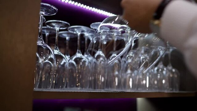 The waiter picks up empty wine glasses. Close-up of hands taking wine glasses. Wine glasses made of glass for wine drinks.