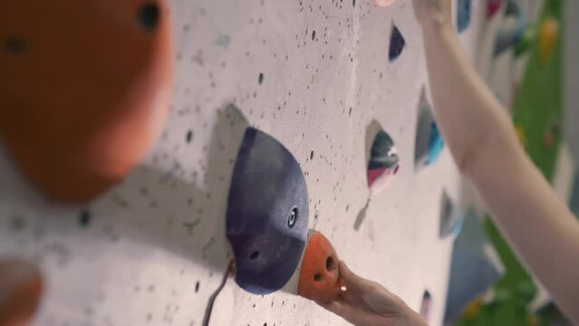 Close up of a female hand gripping a hold on an indoor climbing wall