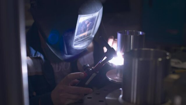A welder makes a precision weld on a stainless-steel element. The element is used for professional kitchen equipment.