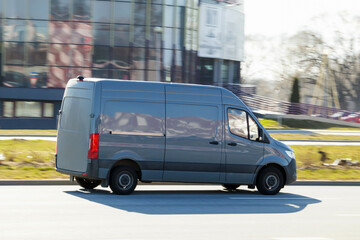 A gray van drives down the street. A moving cargo minibus. Cargo transportation, commercial...
