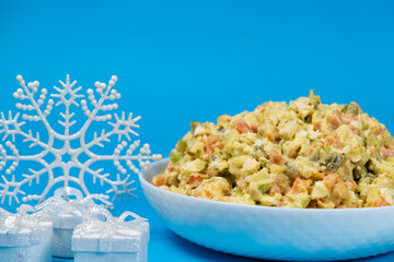 Olivier Russian salad, Christmas and New Year food, blue background with place for text