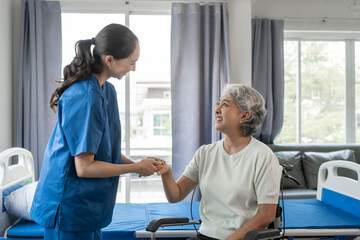 Asian senior care nurses and grandmothers provide caring support to elderly women hand clasp to encourage exercising with elder disabled person patient with caregiver in nursing care.