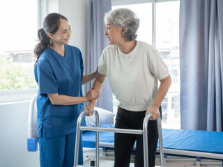 Asian senior care nurses and grandmothers provide caring support to elderly women hand clasp to encourage exercising with elder disabled person patient with caregiver in nursing care.
