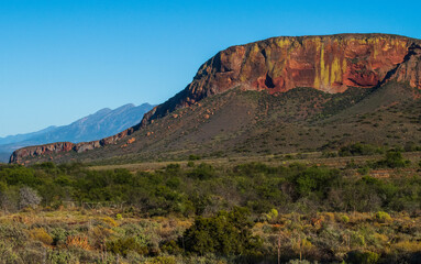 Red  hills near De Rust. A valley with the red hills and the Swartberg mountains in the background.