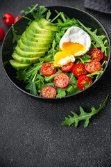 avocado salad poached egg, arugula, tomato, green salad leaves healthy meal food snack on the table copy space food background rustic top view keto or paleo diet veggie vegan or vegetarian food