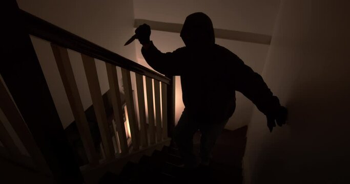 An assassin with a pocket knife sneaks into the house quietly up the stairs at night.