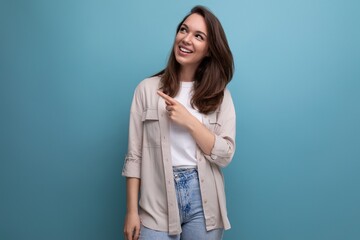 charming brunette 30s woman in shirt and jeans smiling on blue background