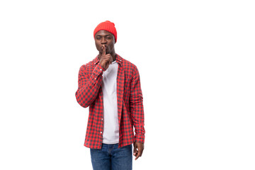 handsome joyful dark-skinned man in a casual plaid shirt keeps a secret on a white background with copy space