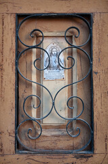 Una placa del corazón de Jesús en una ventana con reja de hierro en un pueblo español.