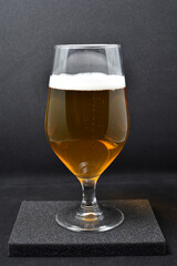 A glass of light beer on a black background. Fresh beer from a glass.
