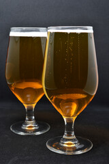 A glass of light beer on a black background. Fresh beer from a glass.