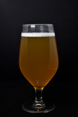 A glass of light beer on a black background. Fresh beer from a glass.