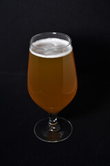 A glass of light beer on a black background. Fresh beer from a glass.