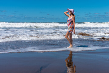 Happy mature woman enjoying walking along the seashore at the beach.