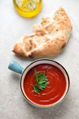Tomato sauce in a turquoise serving bowl and flatbread, vertical shot on a beige stone background, elevated view