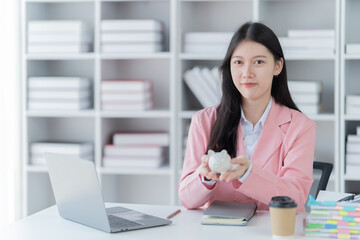 Sharing good business news. Attractive young businesswoman talking on the mobile phone and smiling while sitting at her working place in office and looking at laptop PC.