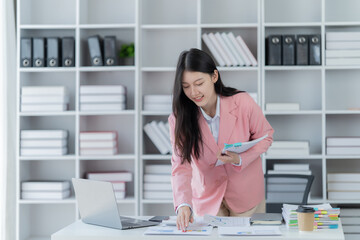 Sharing good business news. Attractive young businesswoman talking on the mobile phone and smiling while sitting at her working place in office and looking at laptop PC.