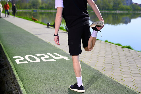 A young man stands by the lake in the morning, warm up, stretch and train near the serene lake, ready for a run.