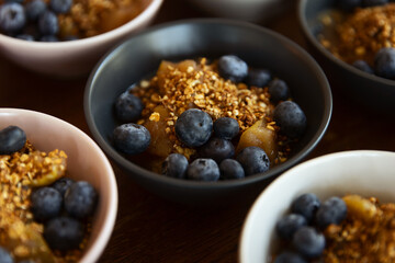 A dessert bowl of blueberries with granola and bits of apple.