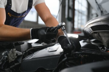 Portrait Shot of a Handsome Mechanic Working on a Vehicle in a Car Service. Modern Clean Workshop.
