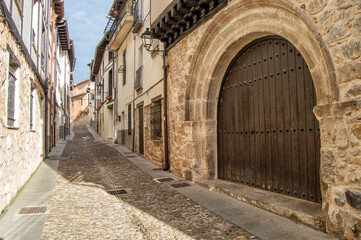 Rural street with a semicircular arch door and old houses in the town of Covarrubias, Burgos province. Spain