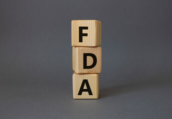 FDA - Food Drug Administration symbol. Wooden cubes with word FDA. Beautiful grey background. Medical and Food Drug Administration concept. Copy space.