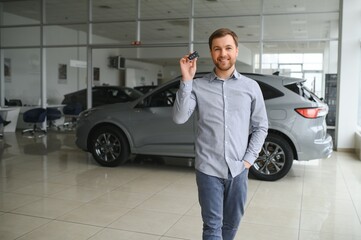 Fototapeta na wymiar a man chooses a new car for himself walks between the rows in a car dealership