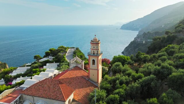 Aerial top view of a sunset over a Church with a bell ringing in a rural area. Chiesa San Pancrazio Martire - a Catholic colourful Church in Conca dei Marini on Amalfi Coast, Italy, Europe in ProRes 4