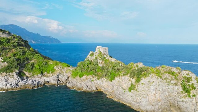 Aerial drone view passing by a Stone Tower on a rocky Coast with blue Sea view. Torre Capo di Conca - a historical landmark on Conca dei Marini, Amalfi COast, Italy, Europe.