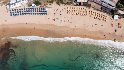 Straight down aerial photo of the beautiful town in Albufeira in Portugal showing the Praia Santa Eulália beach with and people relaxing on vacation on the beach on a hot summers day in the summer.