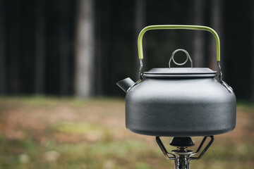 Cooking, heating a tourist kettle on a portable gas burner with a red gas cylinder. Cooking in a...