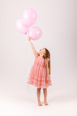 Fototapeta na wymiar Cute smiling little girl in a pink princess dress posing with air balloons isolated on white background. Kids Birthday party celebration concept. Happy Birthday banner with copy space. Studio shot.