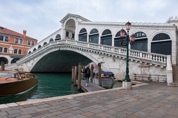 Rialto Bridge in Venice (Italy), with a woman contemplating its canals