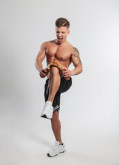 cool emotional strong athletic man with a muscular body in shorts and sneakers breaks a baguette...