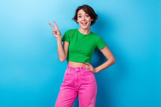 Photo of adorable girl wear stylish t-shirt showing fingers v-sign have fun carefree peaceful lady young age isolated on aquamarine color background